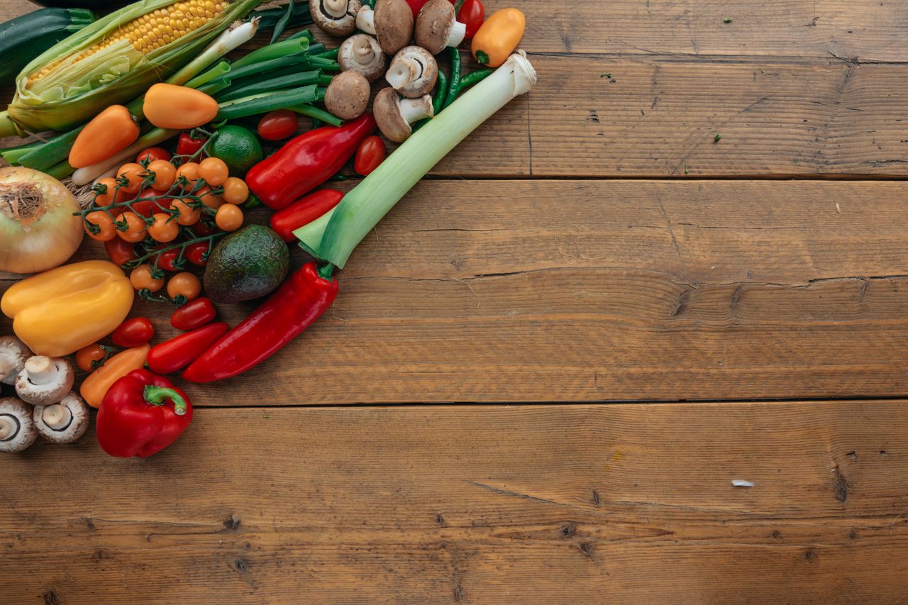 A colorful assortment of fresh vegetables on a wooden table with copy space on the right.