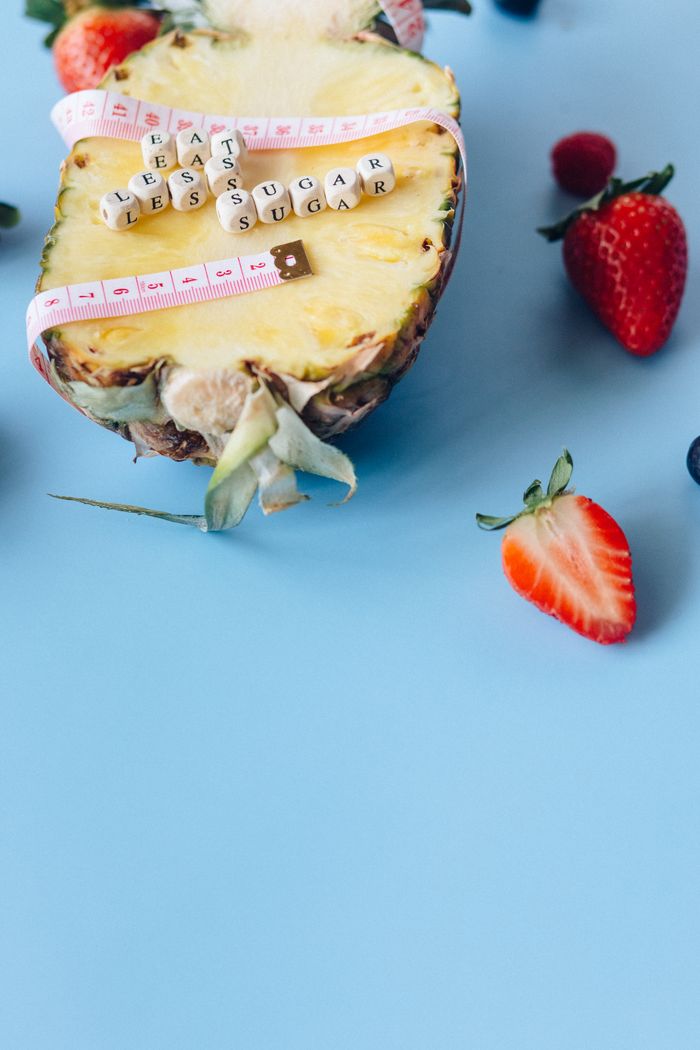 Pineapple surrounded by berries with a health message promoting less sugar intake.