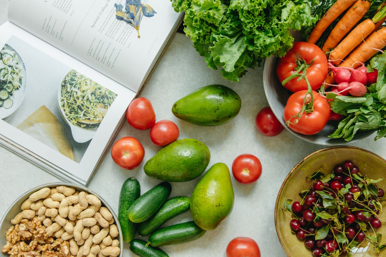 An appetizing display of fresh fruits and vegetables with a cookbook, perfect for healthy recipes.